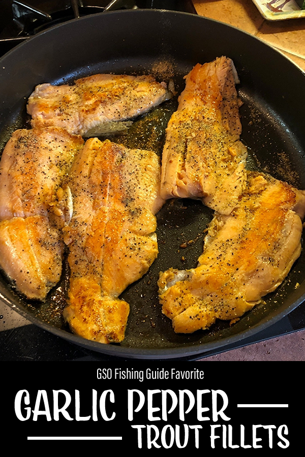 Garlic Pepper Trout: Blue Mesa trout fillets cooking in a cast iron pan with garlic butter and pepper sprinkled on top